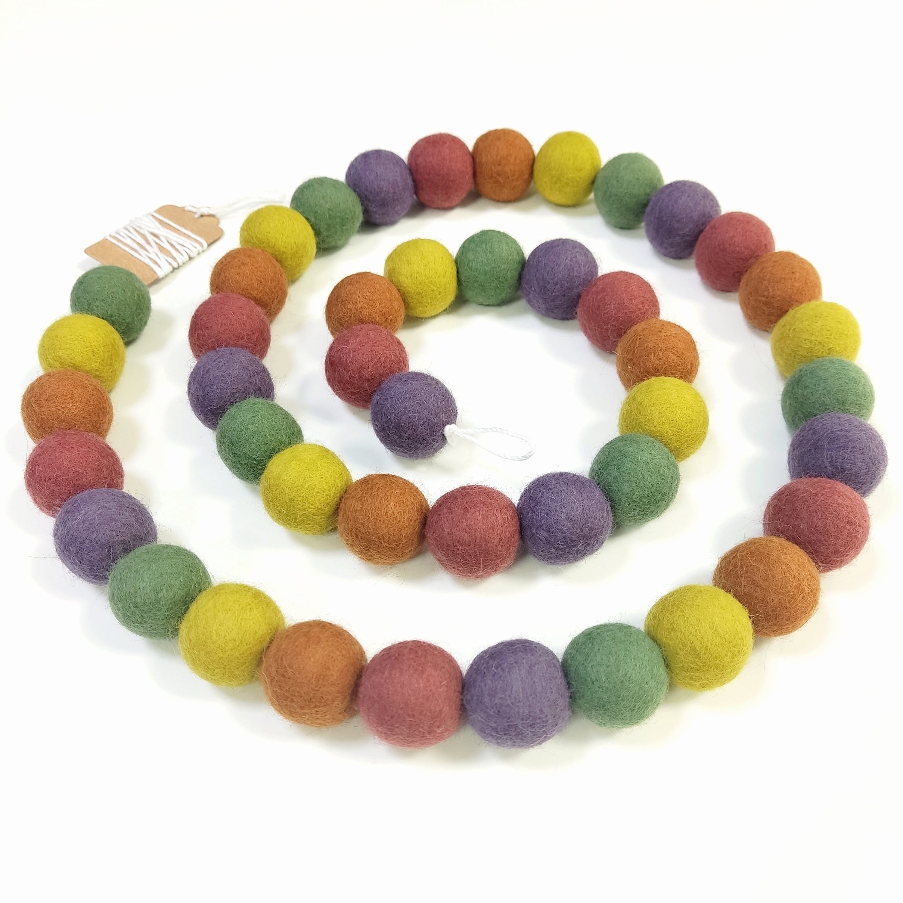 Guirlande de pompons multicolore vintage disposée en spirale sur une table