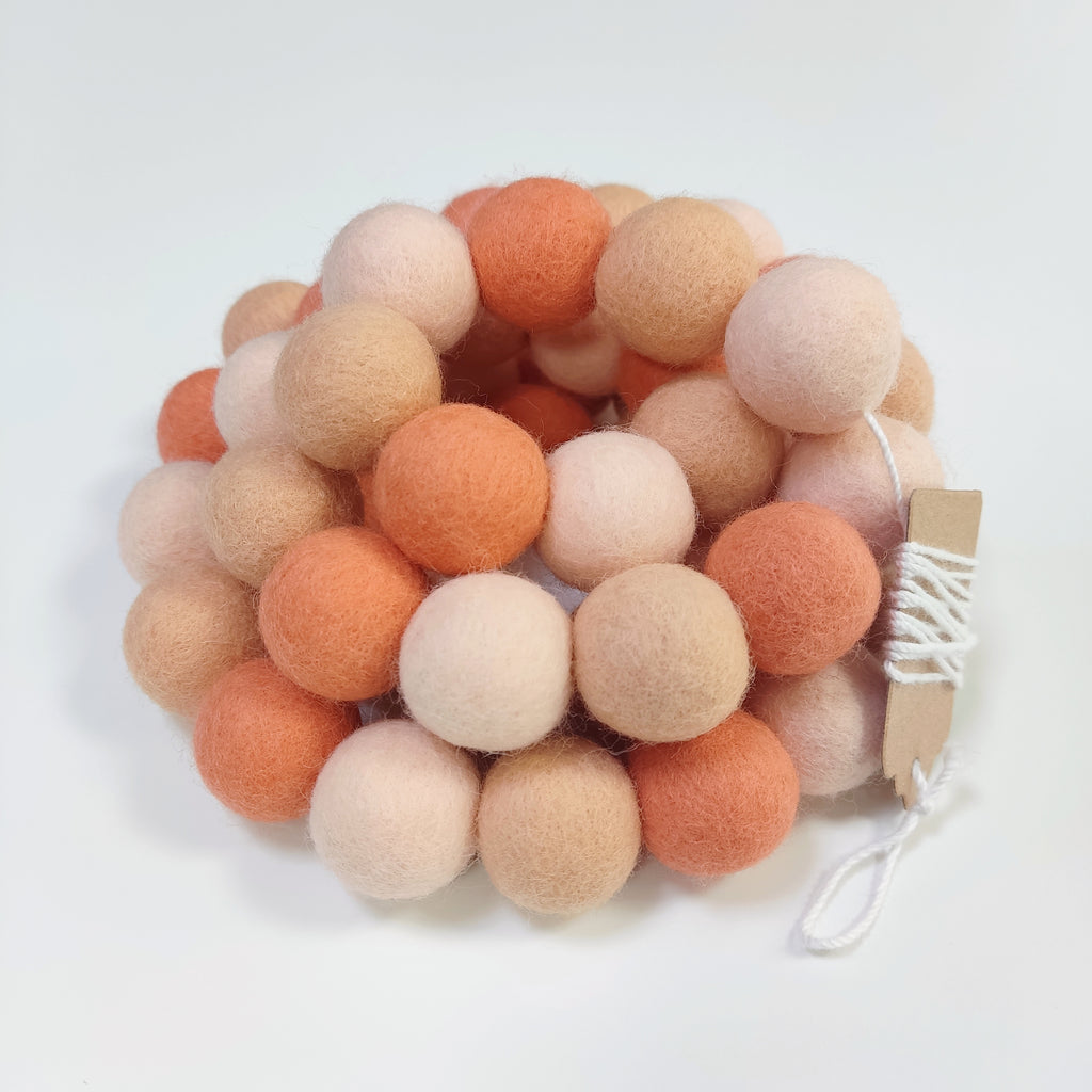 Détails des pompons orange flamingo, beige rosé et orange pêche, vue de près