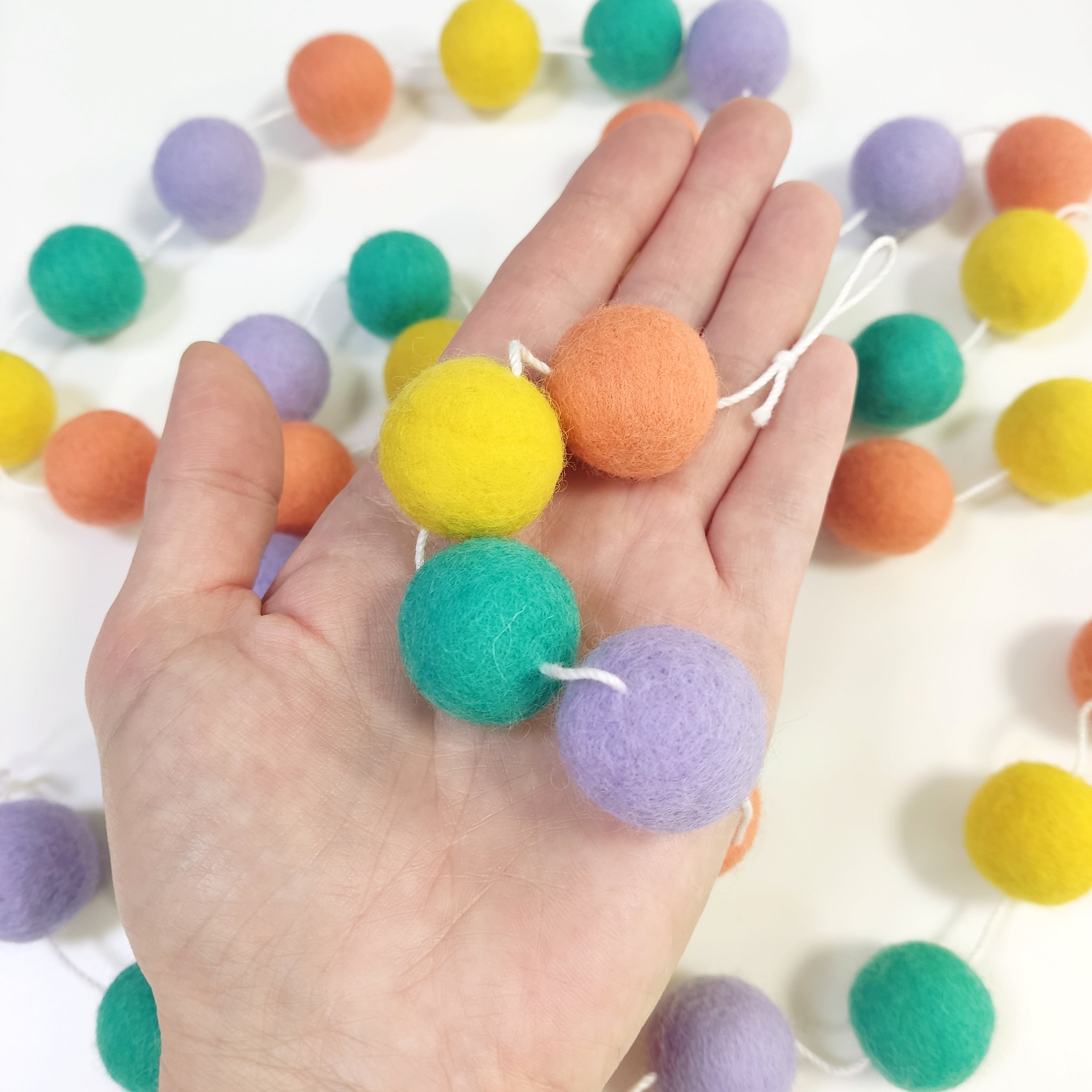 Détails des pompns de 2,5 cm de la guirlande pastel pop dans une main