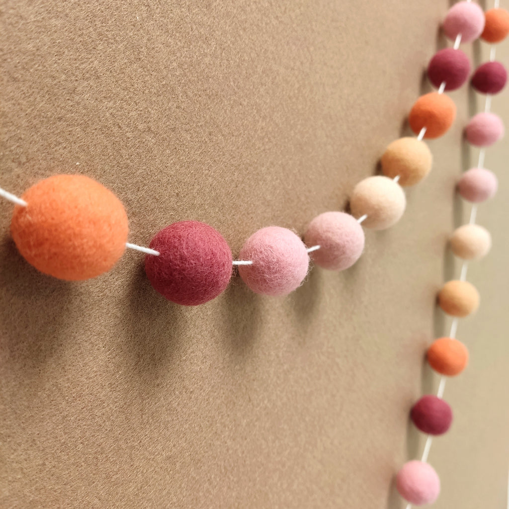Guirlande de pompons rose pêche vue de profil