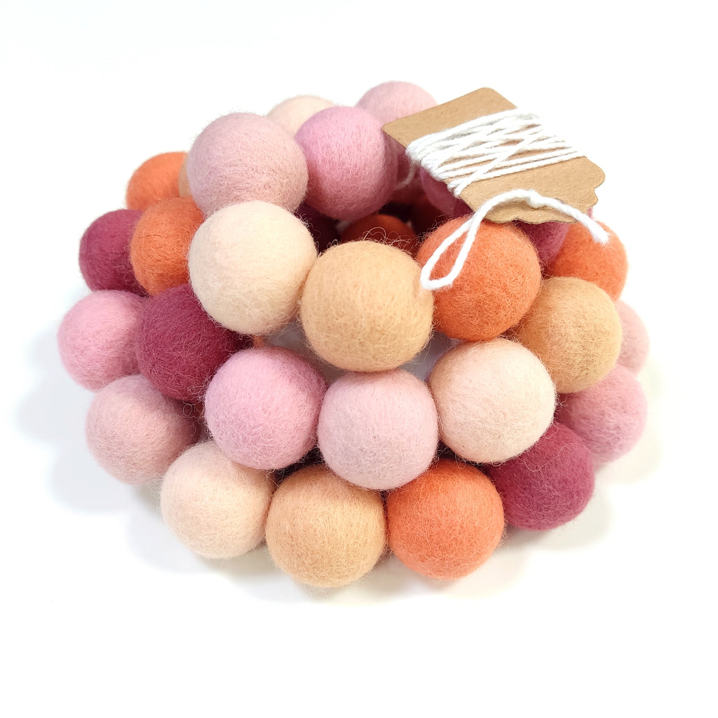 Zoom sur la guirlande de pompons rose pêche et orange avec étiquette