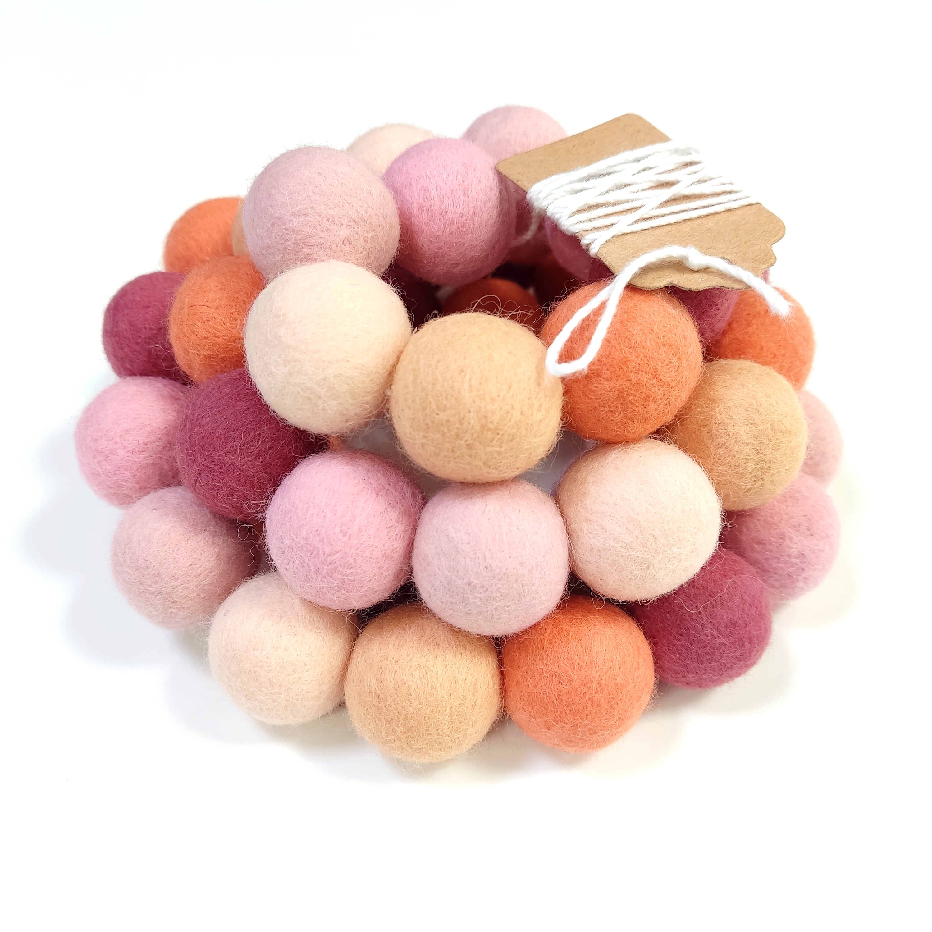 Zoom sur la guirlande de pompons rose pêche et orange avec étiquette