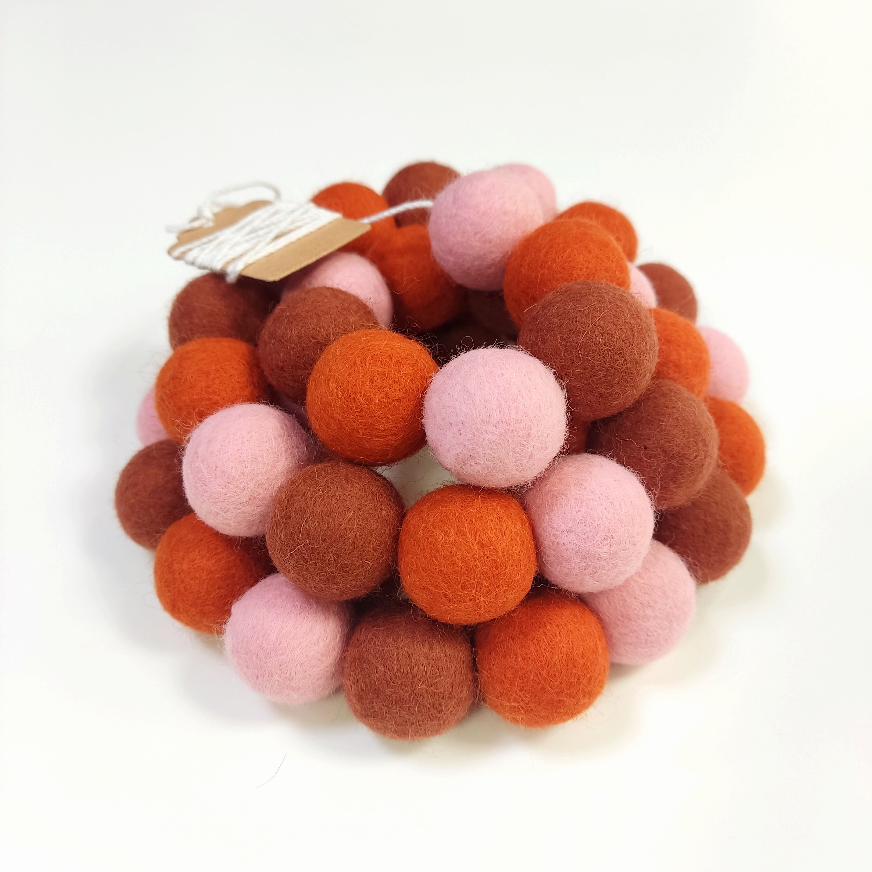 Zoom sur la guirlande de pompons en laine mérinos pétale terracotta avec étiquette CELAINEDECO