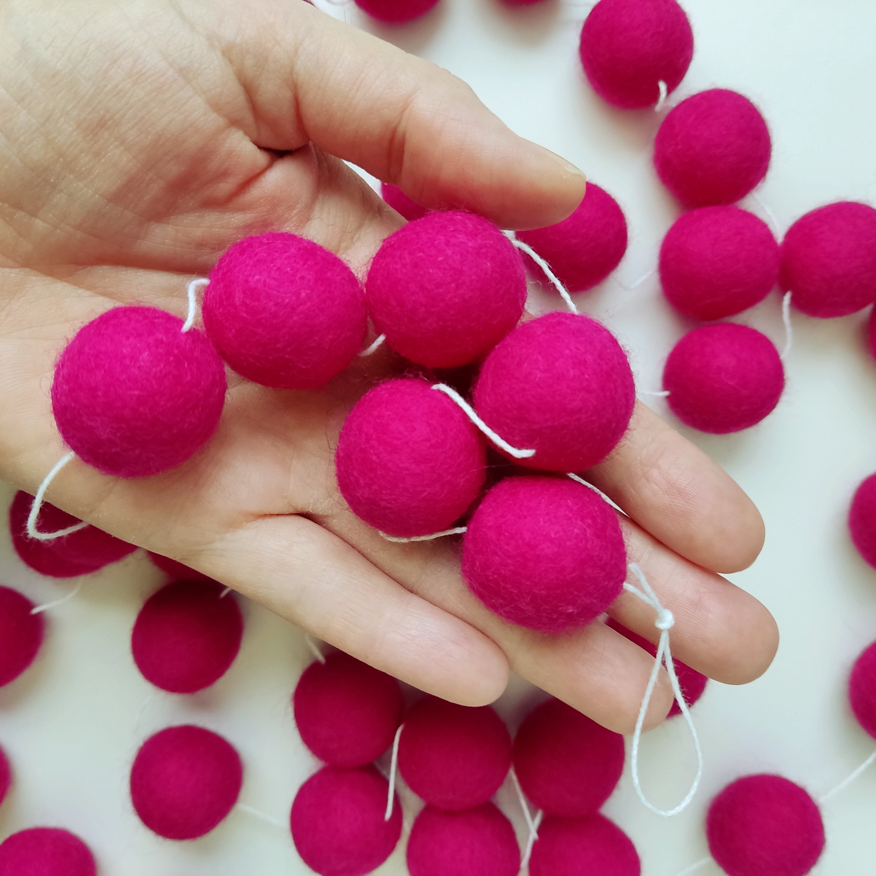 Détails des pompons feutrés roses de la guirlande dans une main