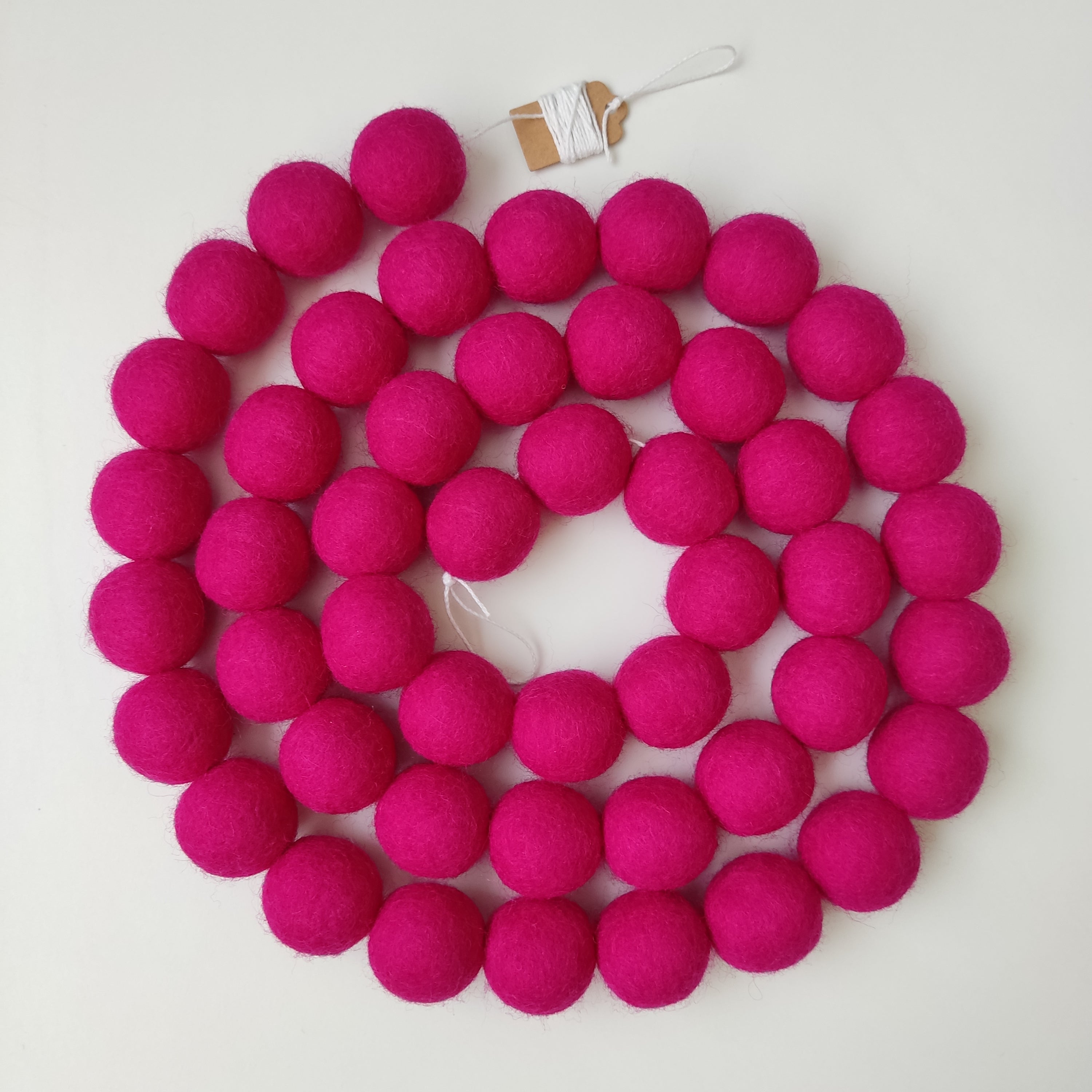 Guirlande en boules de feutre rose magenta enroulée en spirale vue de dessus
