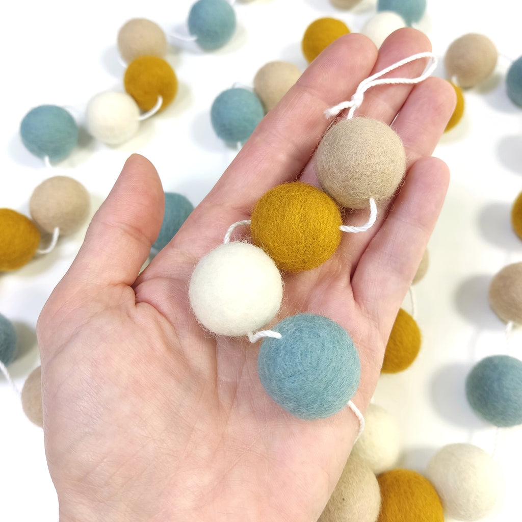 Détail des pompons en feutre de laine mérinos de la guirlande scandinave dans une main
