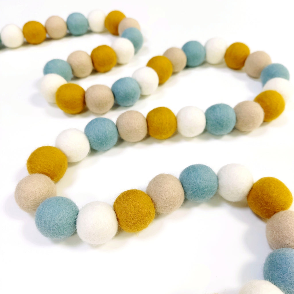 Guirlande de pompons scandinave posée en serpentin sur une table