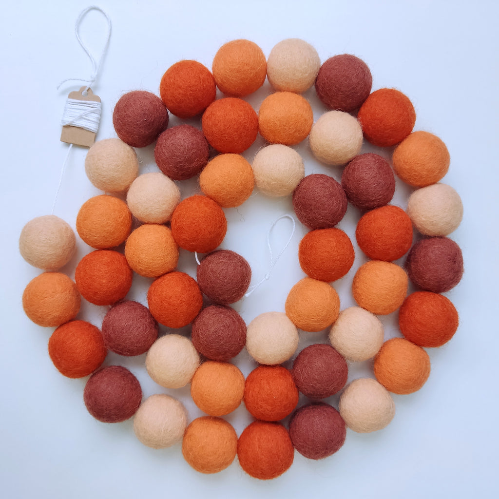 Guirlande en boules de feutres terracotta et orange disposée en spirale vue de dessus