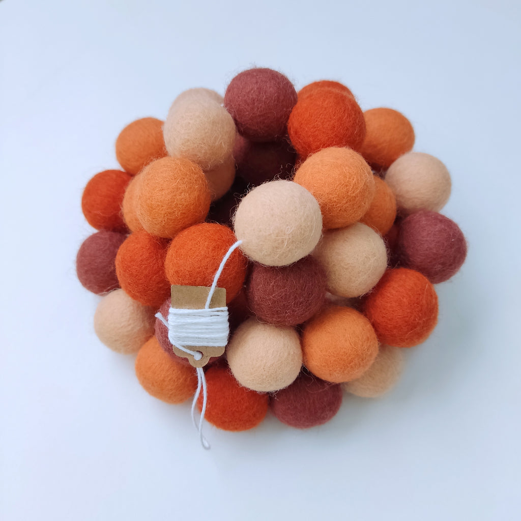 Guirlande chambre d'enfant ou mariage terracotta orange avec pompons resserrés sur le fil et enroulée sur elle-même