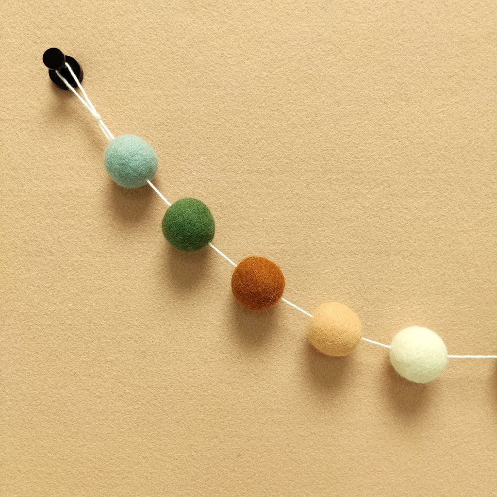 Zoom sur les 5 couleurs de la guirlande terracotta sauge en boules de feutre terracotta cuivre, vert matcha, orange pêche, blanc et vert céladon