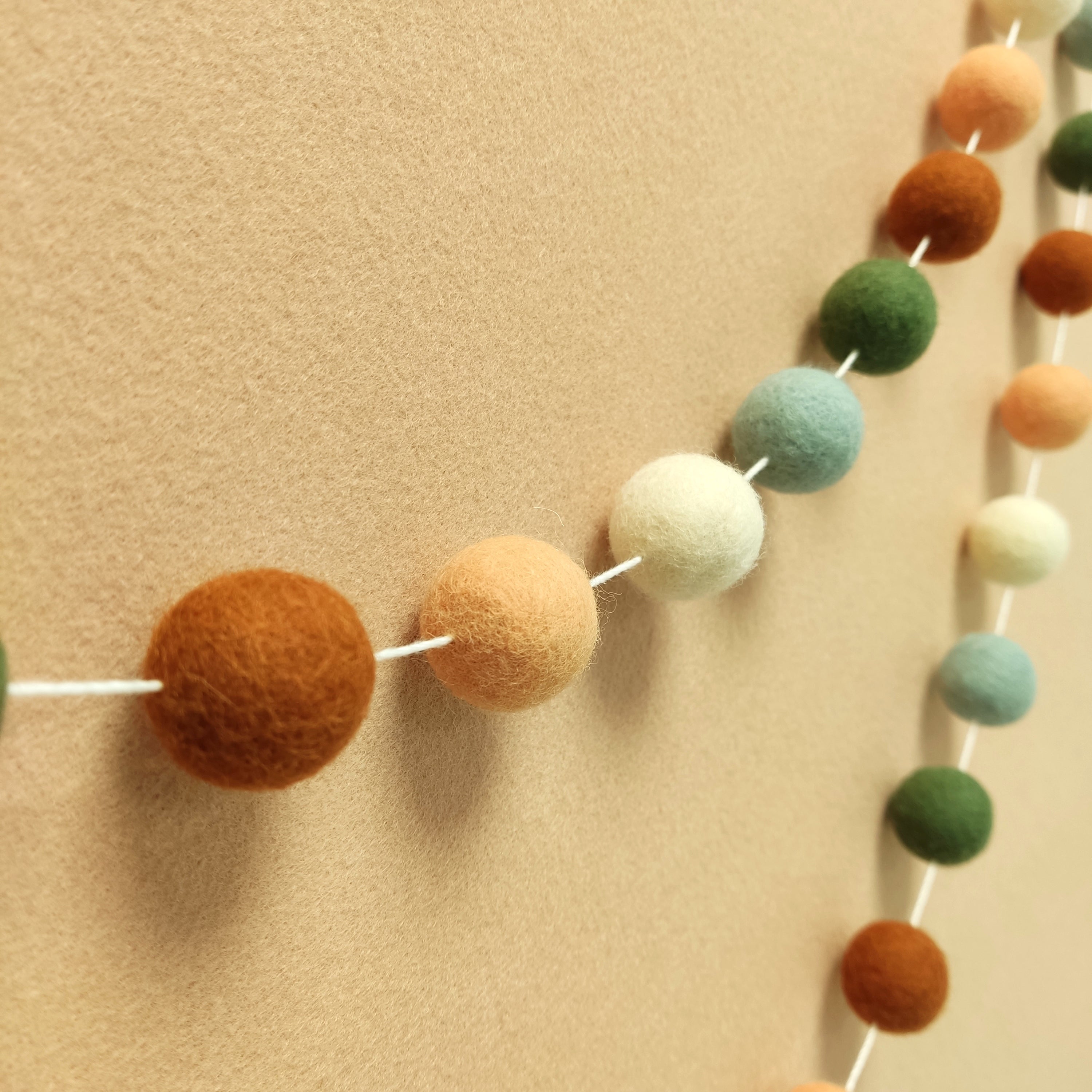 Guirlande de pompons feutrés terracotta sauge blanc vue de profil