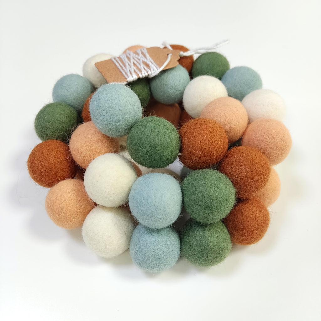 Guirlande en boules de laine feutrée vert blanc terracotta enroulée sur elle-même