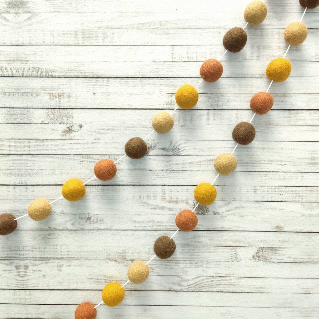 Guirlande pompons marron beige terracotta et ocre pour décoration murale