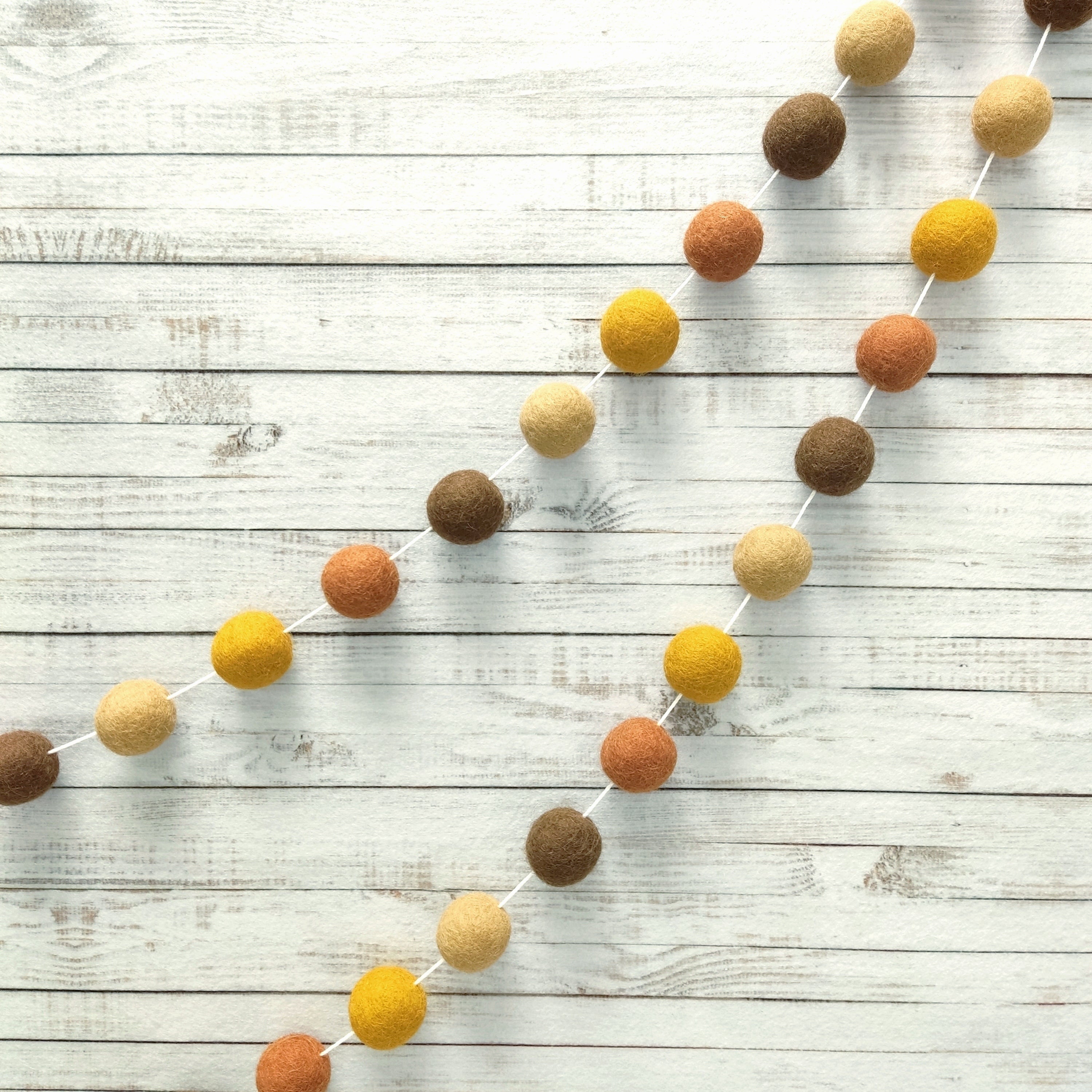 Guirlande pompons marron beige terracotta et ocre pour décoration murale
