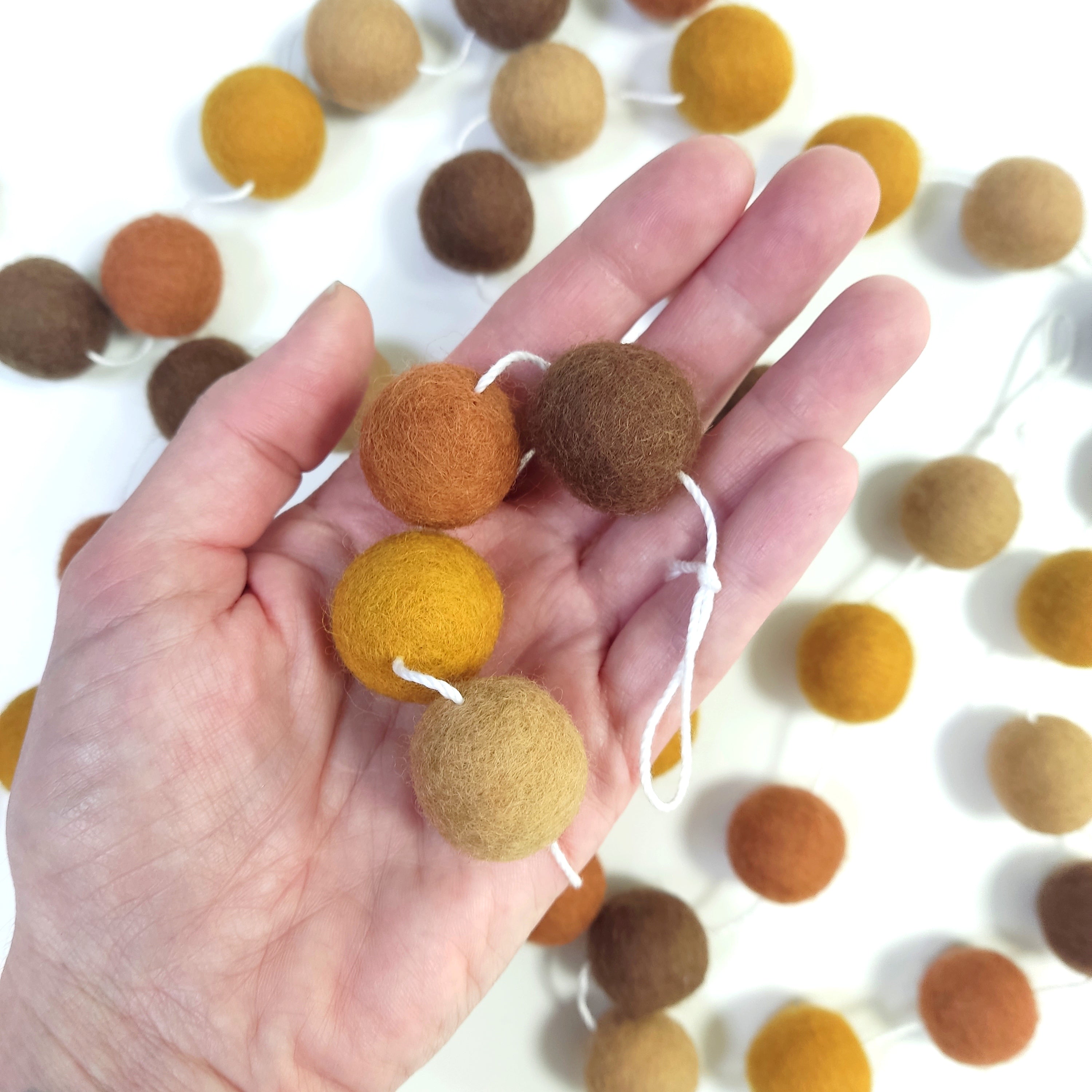 4 boules de feutre de 2,5 cm de la guirlande terre et ocre dans une main