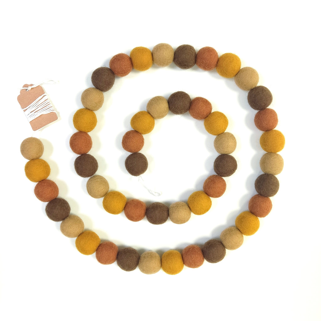 Guirlande en boules de feutre brun, beige ocre, terracotta disposée en spirale vue de dessus