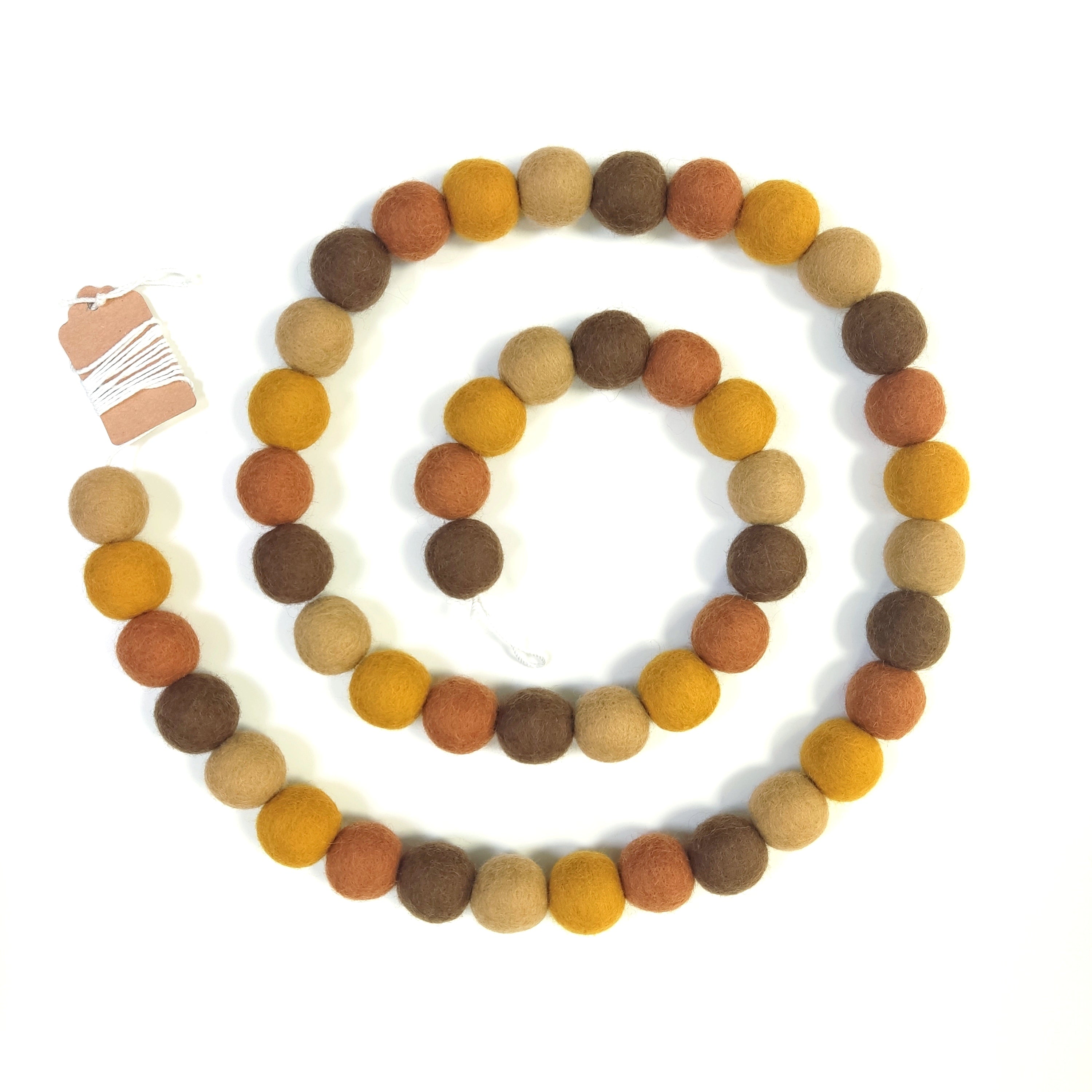 Guirlande en boules de feutre brun, beige ocre, terracotta disposée en spirale vue de dessus