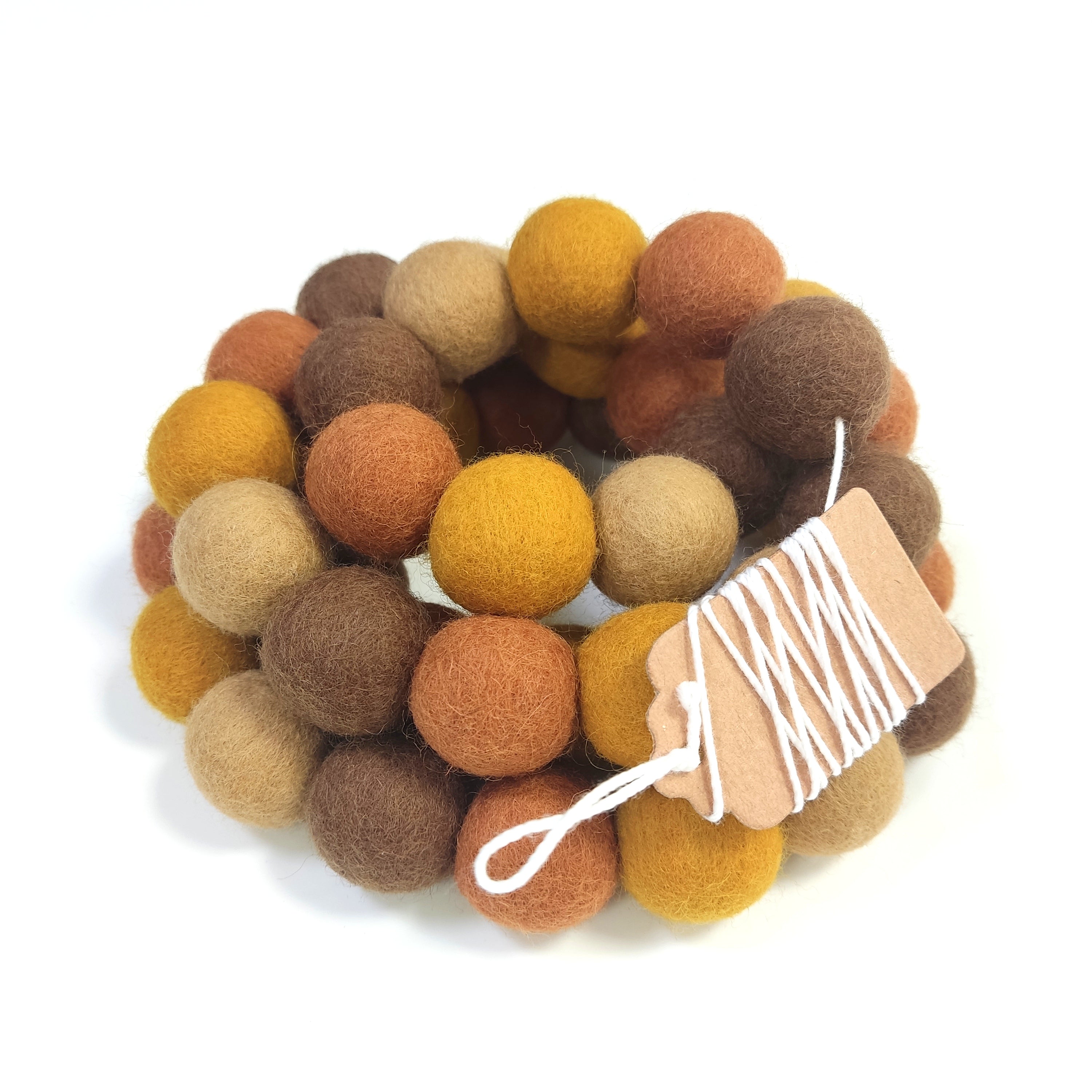 Guirlande terre et ocre avec pompons rassemblés sur le fil et enroulée sur elle-même