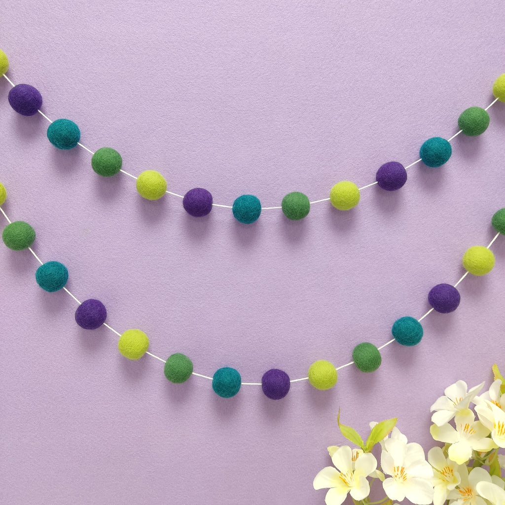 Guirlande de pompons feutrés vert citron, vert feuille, violet et vert canard en décoration murale, faite main en France