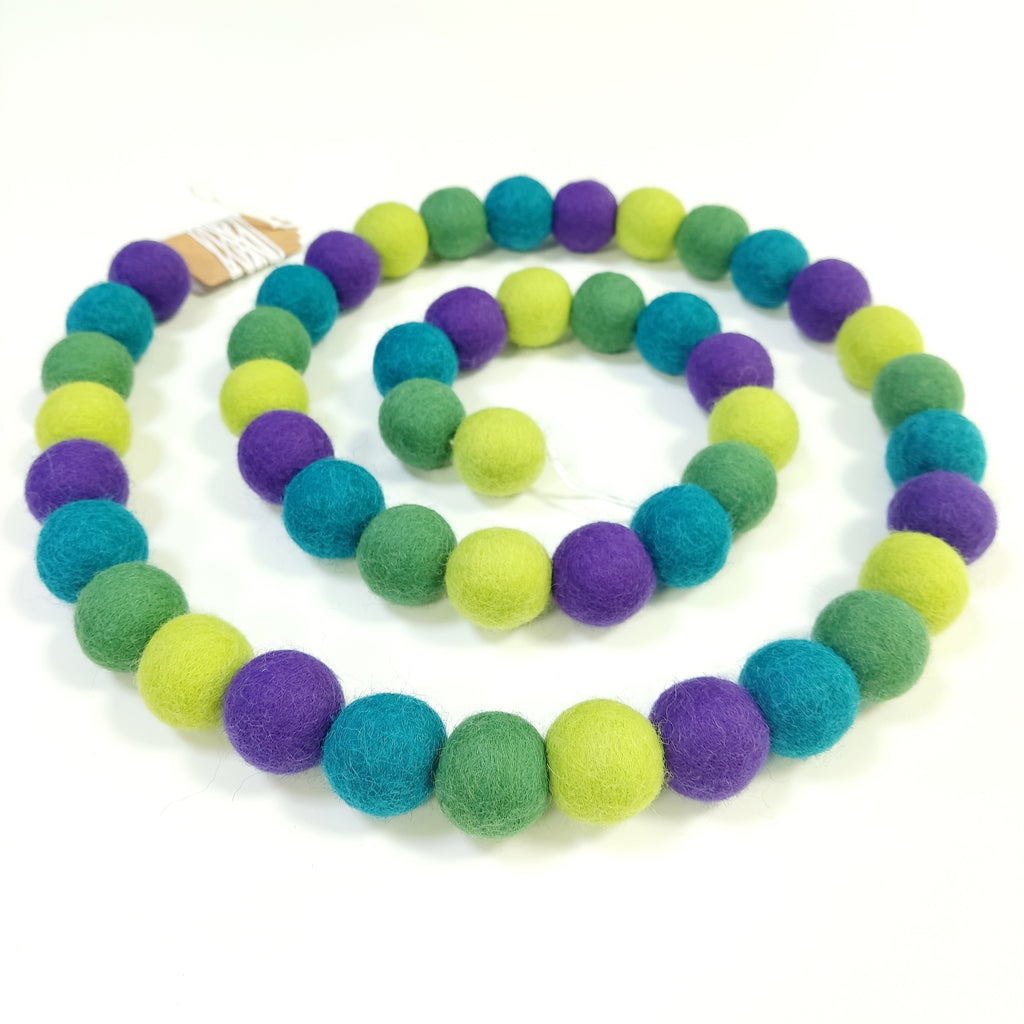 Guirlande de pompons de feutre vert violet disposée en spirale vue de dessus