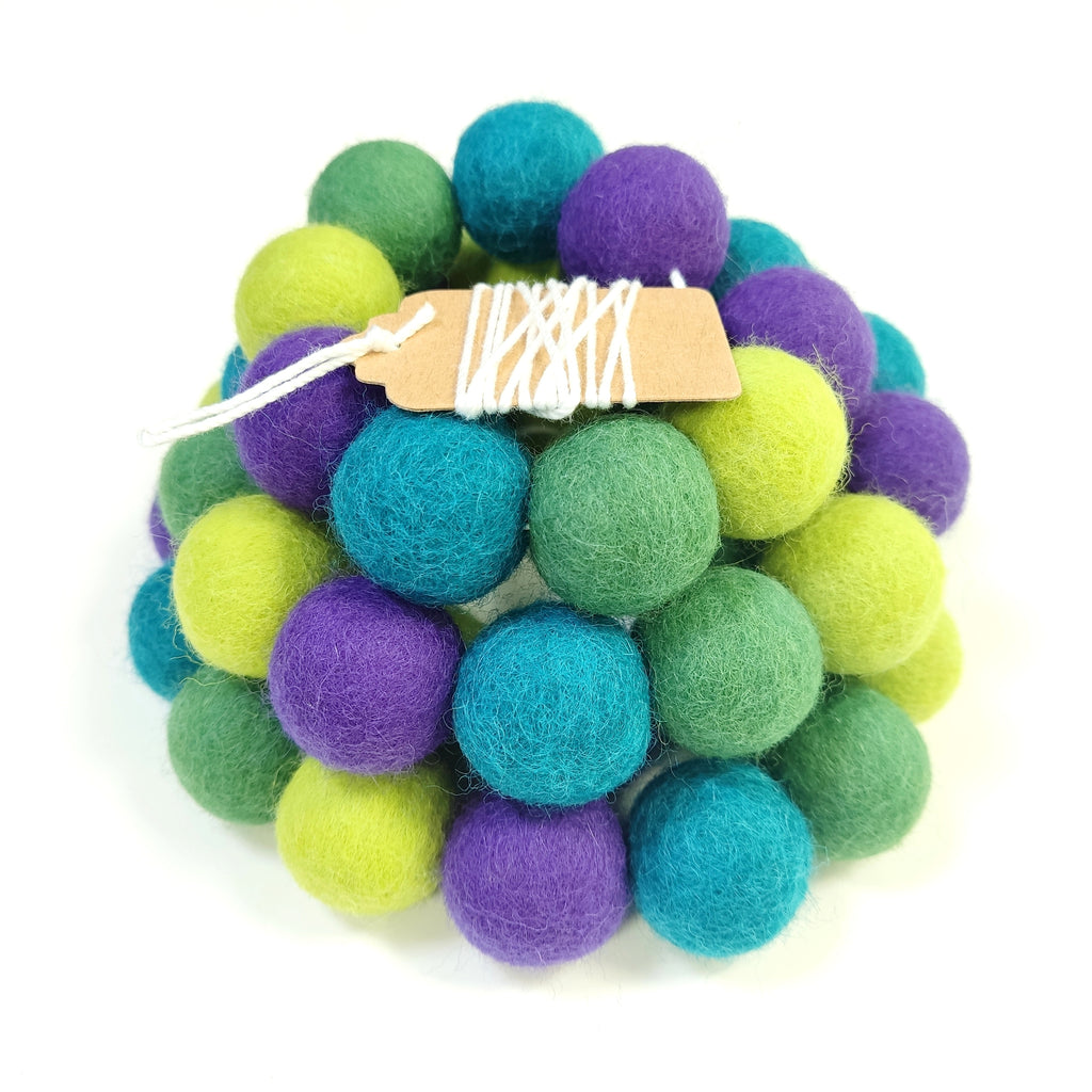 Zoom sur la guirlande de pompons vert violet avec étiquette