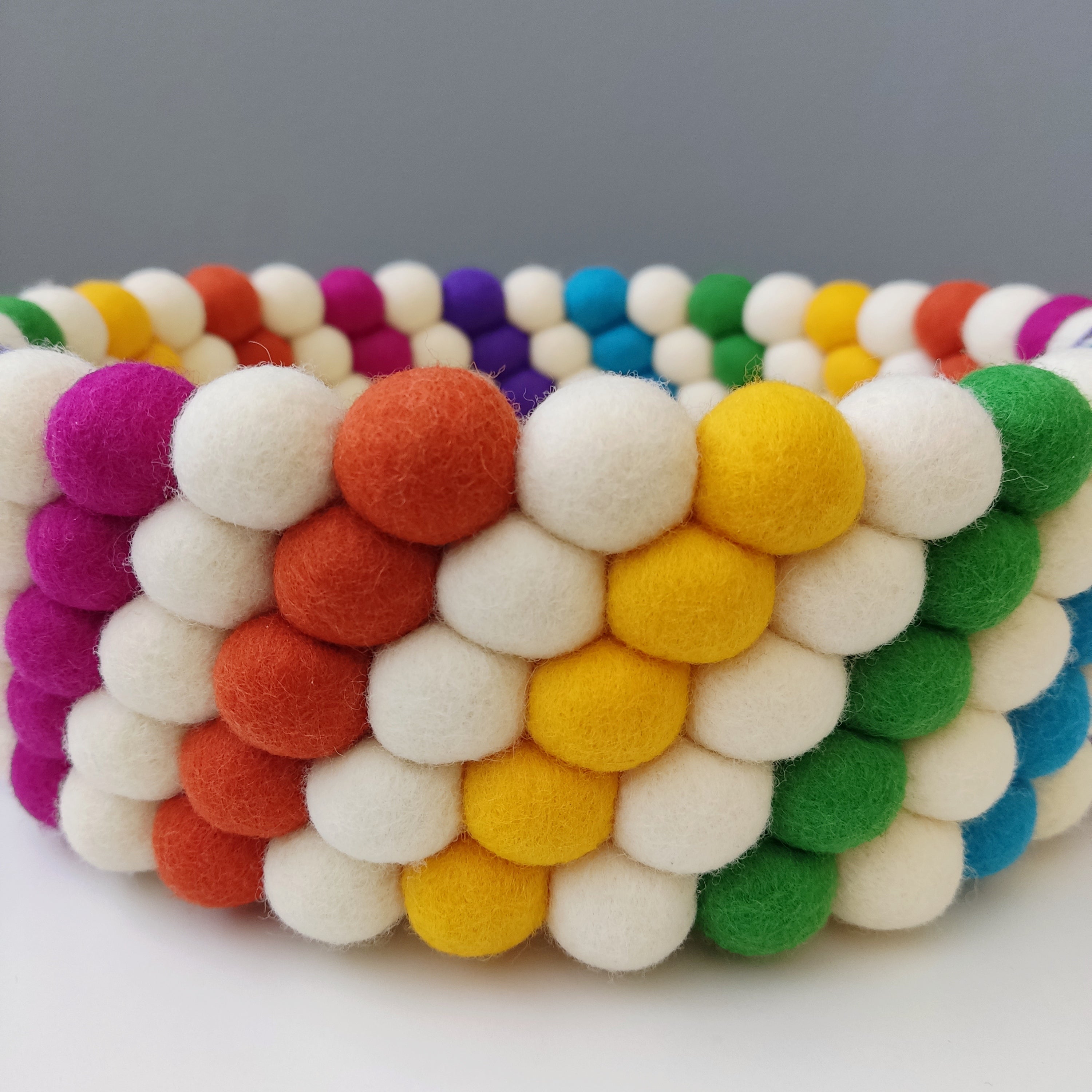 Zoom sur le panier blanc et arc-en-ciel en pompons feutrés mérinos  – CELAINEDECO