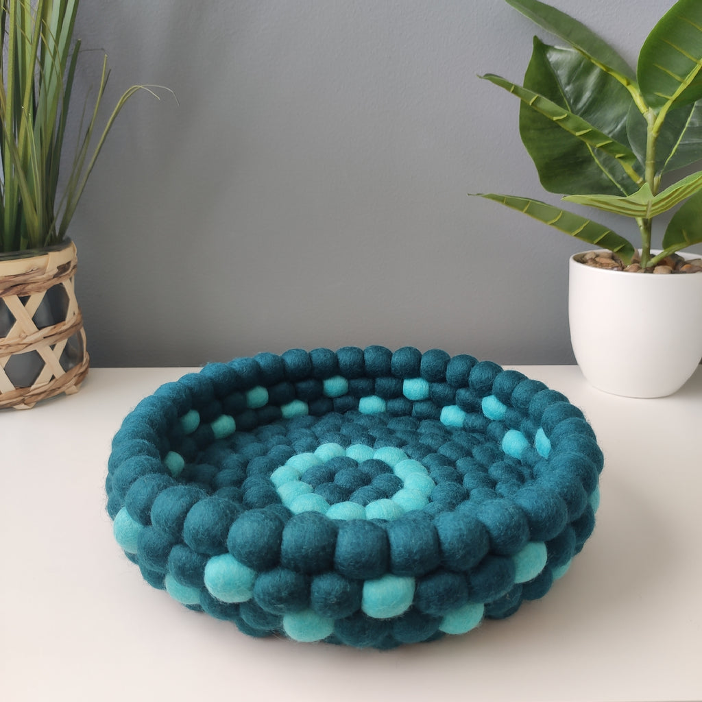 Panier pompons laine mérinos bleu pétrole et lagon posé sur meuble – décoration CELAINEDECO