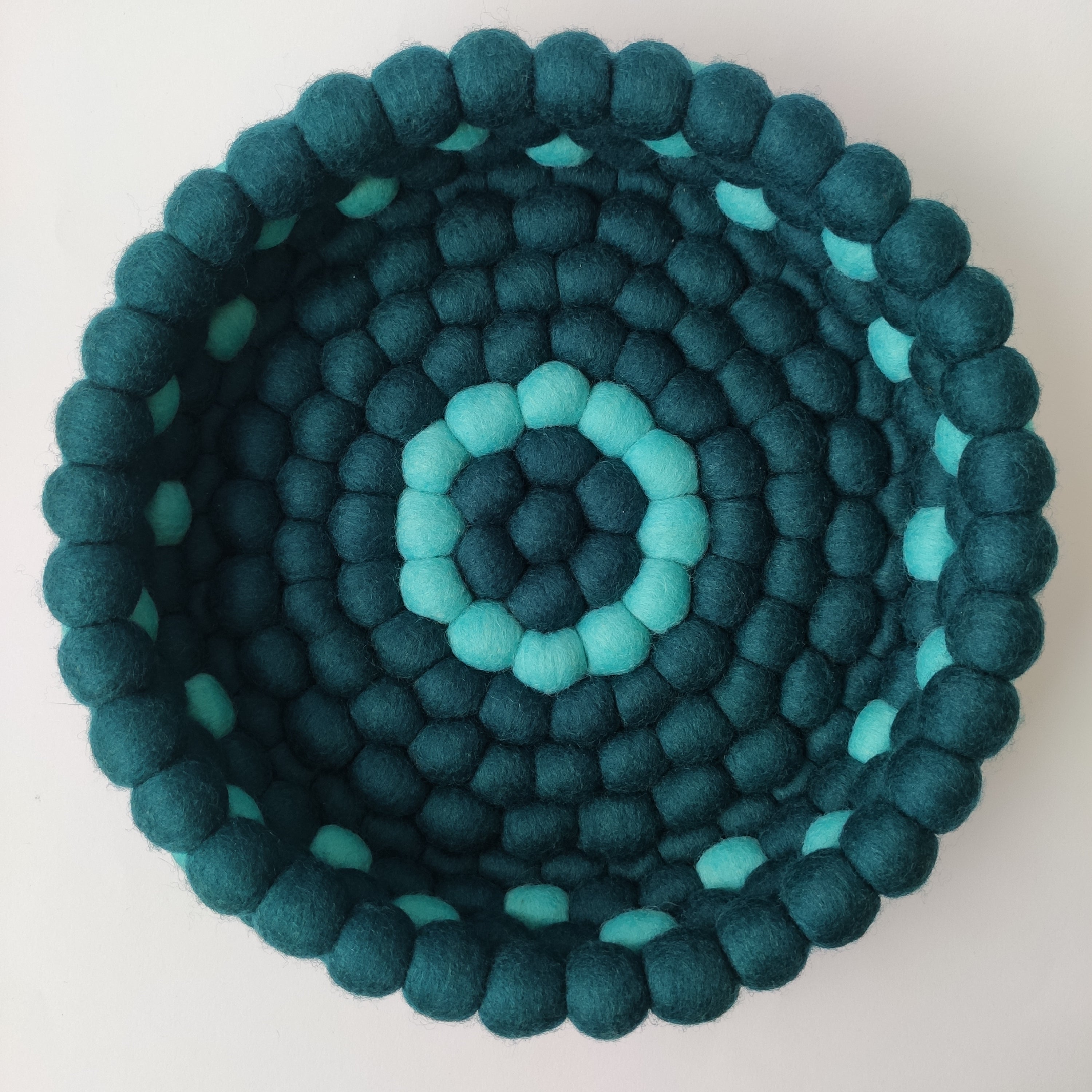 Panier rond pompons feutrés Horizon Marin vu de dessus – anneaux concentriques bleu pétrole et lagon