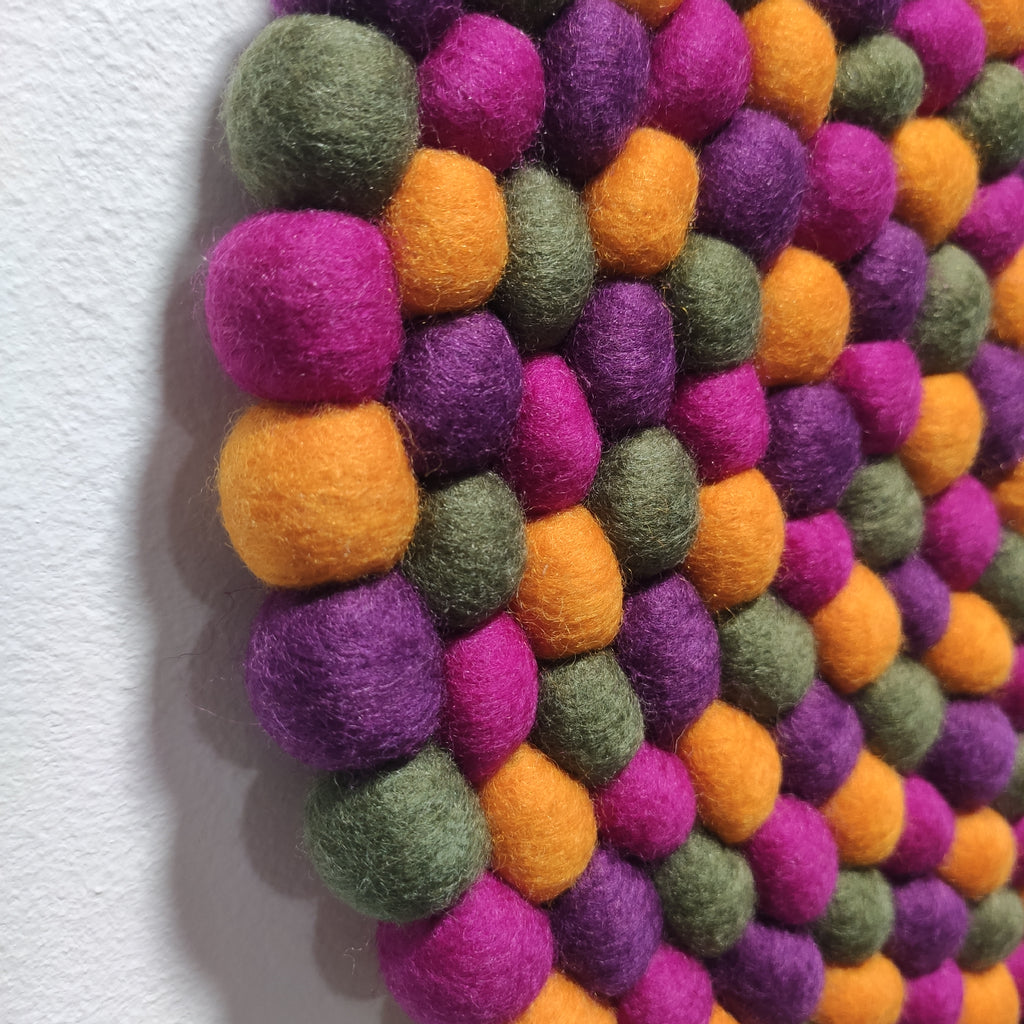 Détail de la tapisserie murale Dahlia – pompons en laine mérinos feutrée rose fuchsia, marigold, violine et vert olive – pièce unique faite en France
