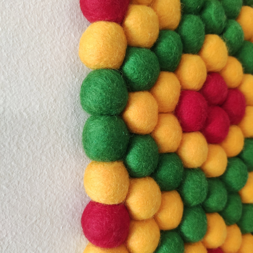 Tapisserie murale Fiesta – Détail des pompons feutrés vert prairie, jaune tournesol et rouge coquelicot