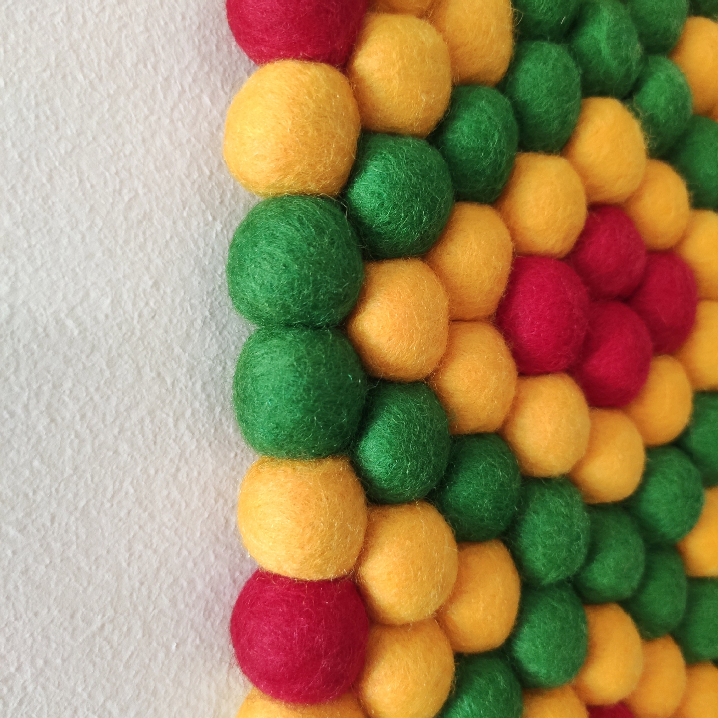 Tapisserie murale Fiesta – Détail des pompons feutrés vert prairie, jaune tournesol et rouge coquelicot