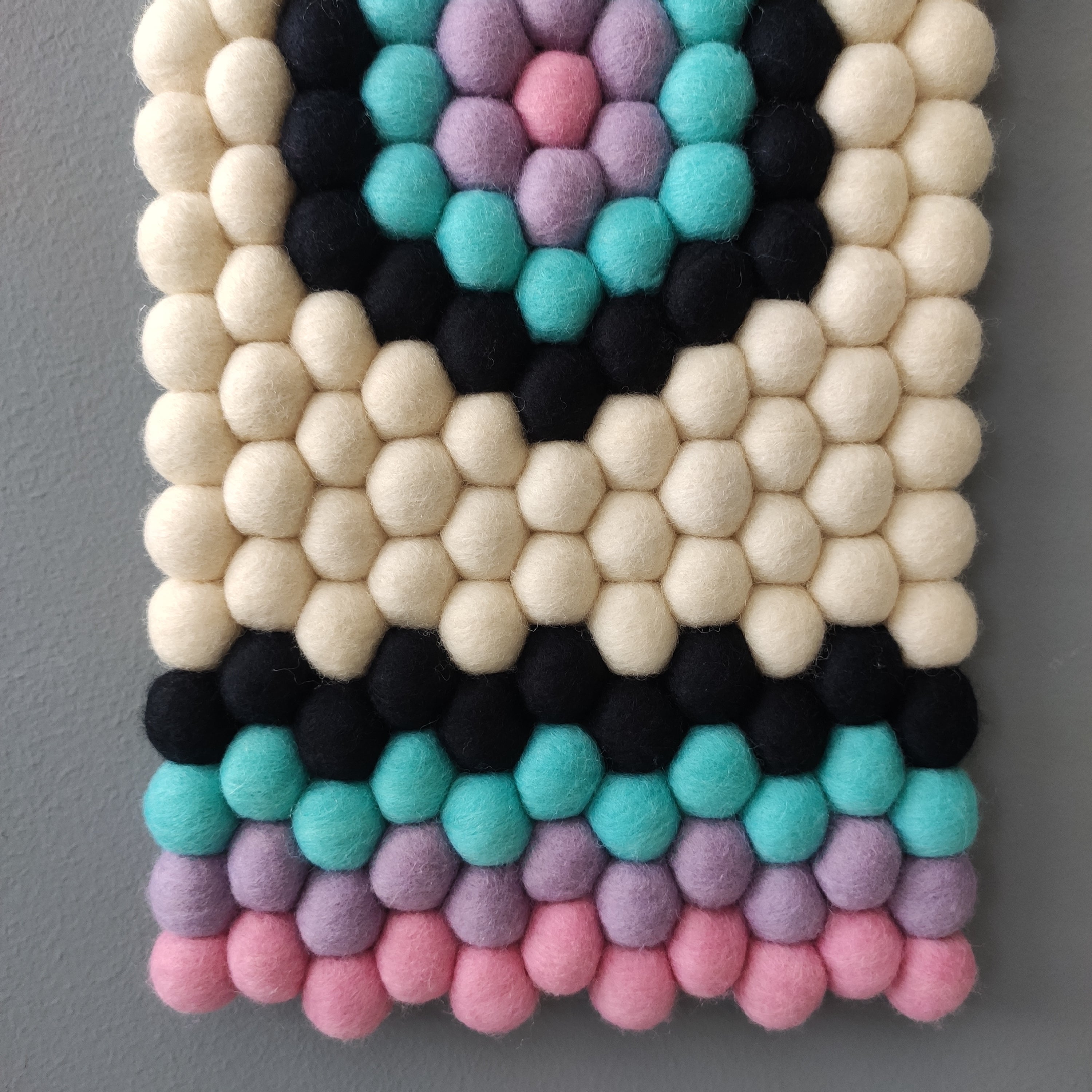 Détail du motif hexagonal de la tapisserie murale Kaléidoscope – pompons en laine Mérinos aux couleurs contrastées – CELAINEDECO