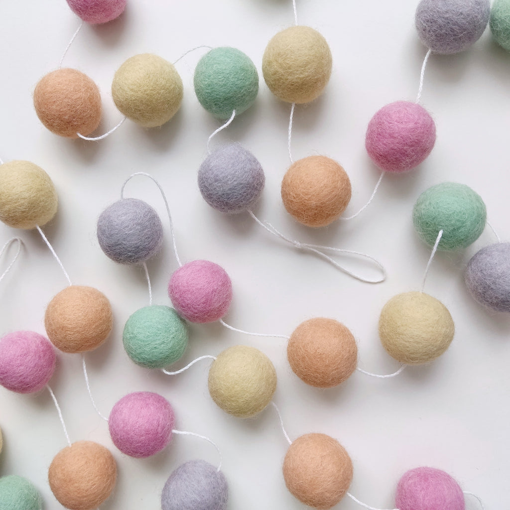 Guirlande de pompons aux couleurs pastel licorne étalée sur une table