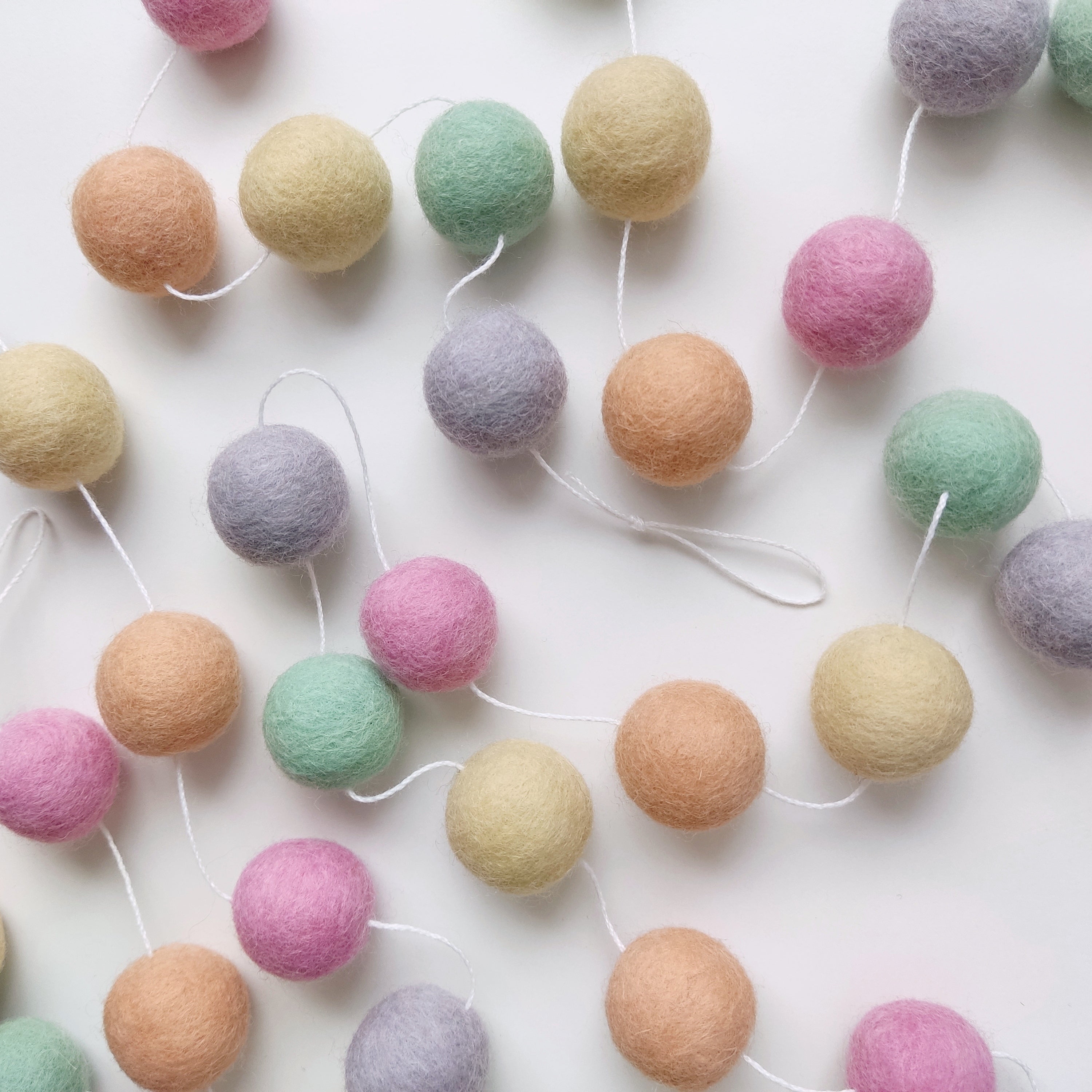 Guirlande de pompons aux couleurs pastel licorne étalée sur une table