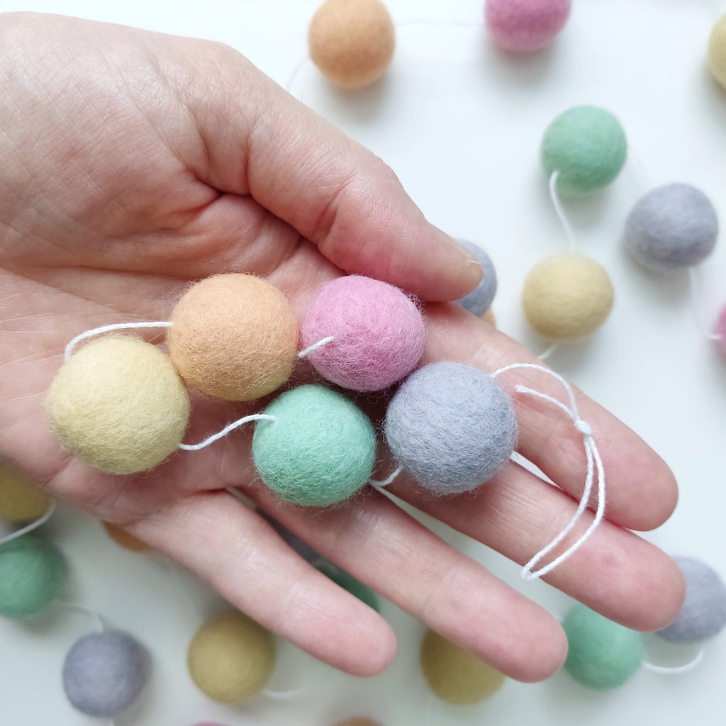 5 couleurs de pompons de la guirlande licorne pastel dans une main