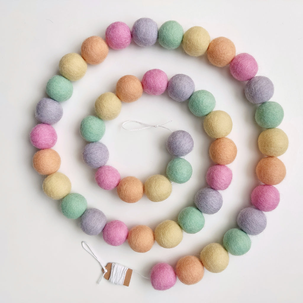 Guirlande aux couleurs licorne pastel disposée en spirale sur une table vue de dessus